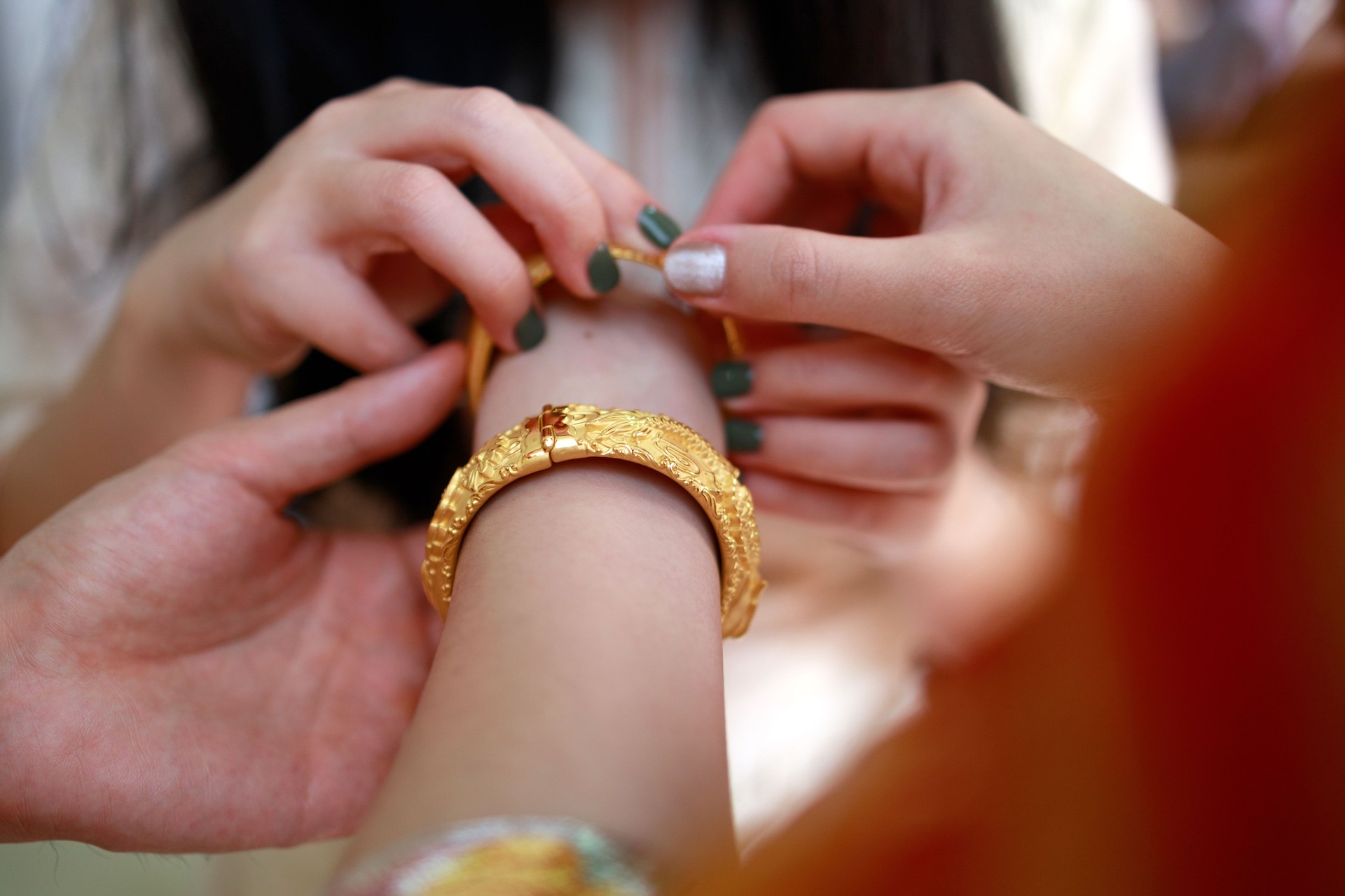 Close up hands of bride gifted with gold bangle by family during tea ceremony, tradition in Chinese wedding.